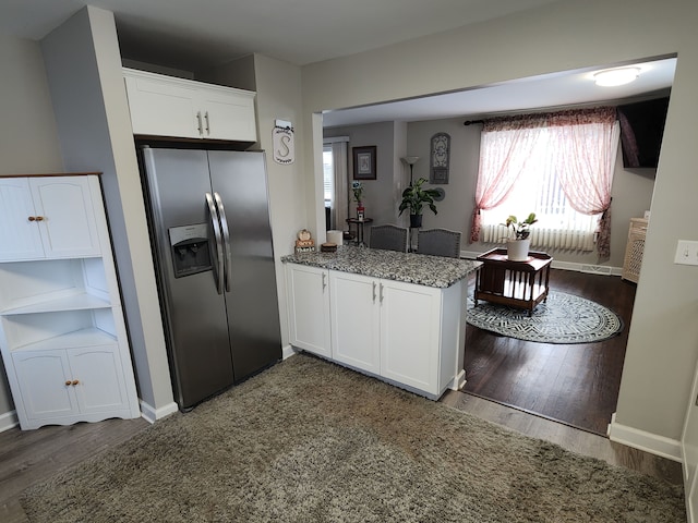 kitchen featuring kitchen peninsula, stainless steel fridge, dark stone counters, dark hardwood / wood-style floors, and white cabinetry