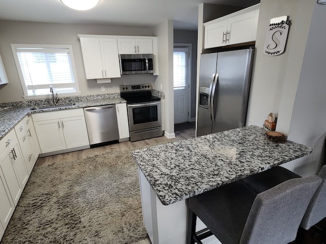 kitchen with light hardwood / wood-style flooring, stainless steel appliances, white cabinetry, and sink