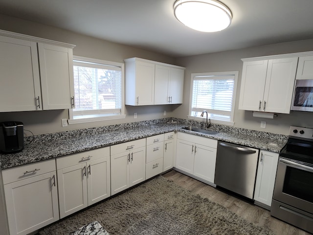 kitchen with white cabinetry, sink, stainless steel appliances, and wood-type flooring