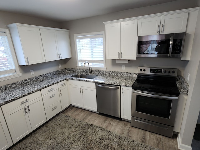 kitchen with sink, white cabinets, stainless steel appliances, and hardwood / wood-style flooring