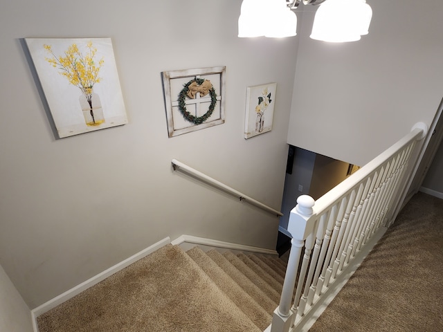 stairs with carpet floors and a notable chandelier