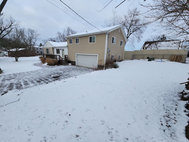 snow covered house featuring a garage