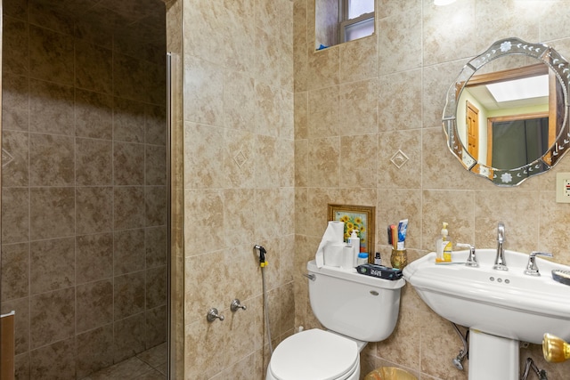 bathroom with sink, toilet, and tile walls