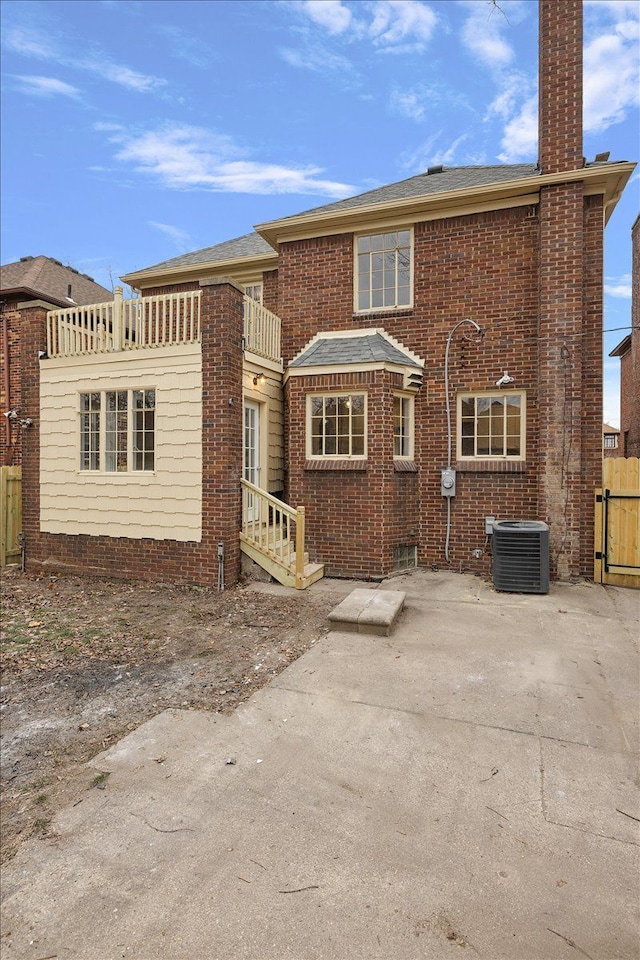 back of property with a balcony, central AC unit, and a patio area