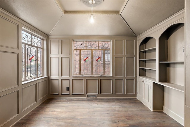 unfurnished room featuring ornamental molding, dark hardwood / wood-style floors, built in features, and lofted ceiling