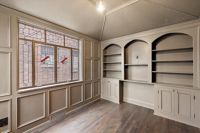 unfurnished office featuring built in shelves, dark hardwood / wood-style floors, and ornamental molding