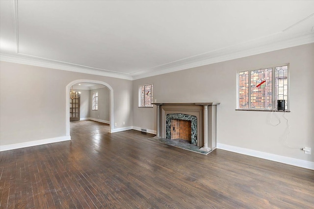 unfurnished living room with a healthy amount of sunlight, crown molding, and dark wood-type flooring