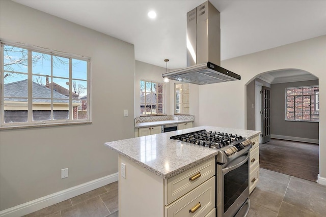 kitchen with light stone counters, a wealth of natural light, gas range, island range hood, and hanging light fixtures