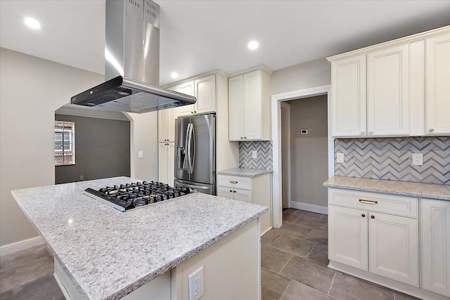 kitchen with decorative backsplash, island range hood, light stone countertops, and appliances with stainless steel finishes