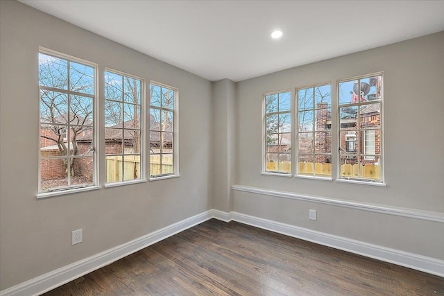 spare room with dark hardwood / wood-style flooring and a wealth of natural light