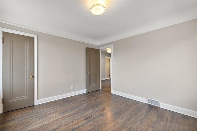 empty room with dark hardwood / wood-style flooring and crown molding