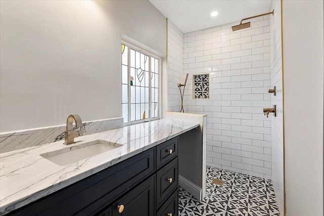 bathroom with a tile shower, tile patterned flooring, and vanity