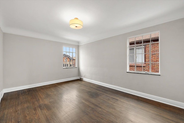 empty room featuring ornamental molding and dark wood-type flooring