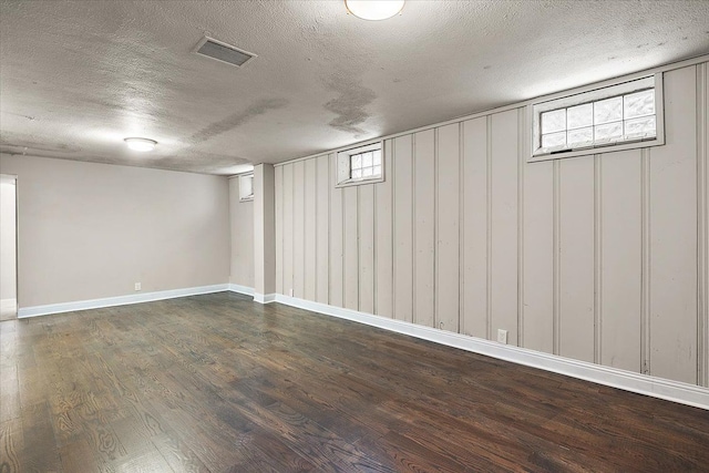 basement featuring a textured ceiling and dark hardwood / wood-style floors