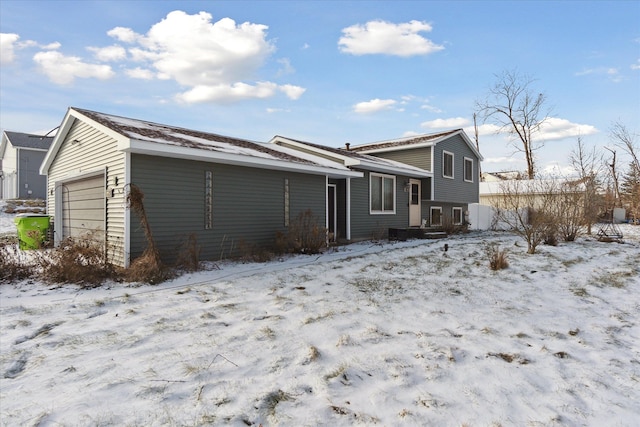 snow covered house featuring a garage