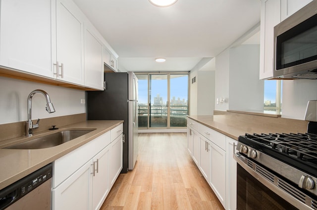 kitchen featuring floor to ceiling windows, white cabinetry, and stainless steel appliances