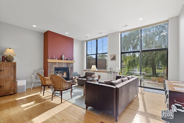 living room featuring floor to ceiling windows, a fireplace, and light hardwood / wood-style flooring