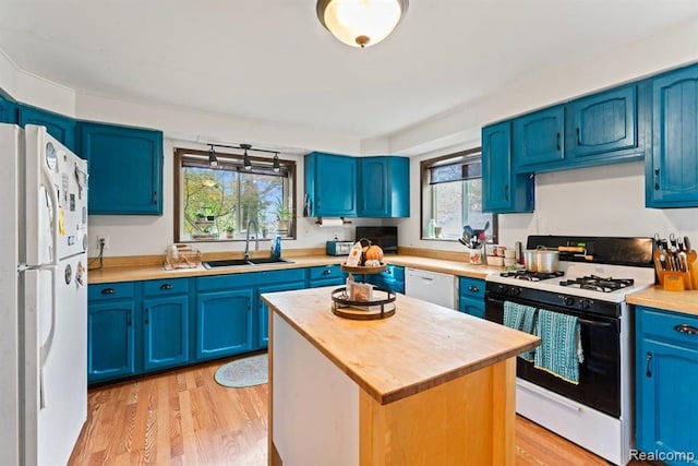 kitchen featuring sink, blue cabinets, white appliances, a kitchen island, and light wood-type flooring