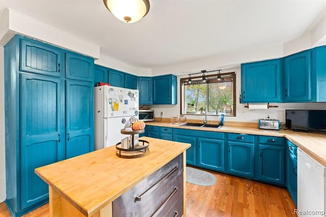 kitchen featuring white appliances, light hardwood / wood-style floors, blue cabinets, and sink