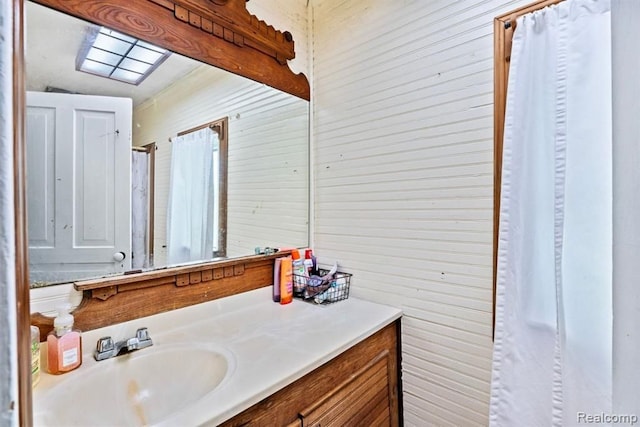 bathroom with vanity, lofted ceiling, and wood walls