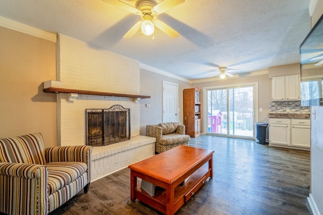 living room with dark hardwood / wood-style flooring, ornamental molding, a textured ceiling, and a brick fireplace