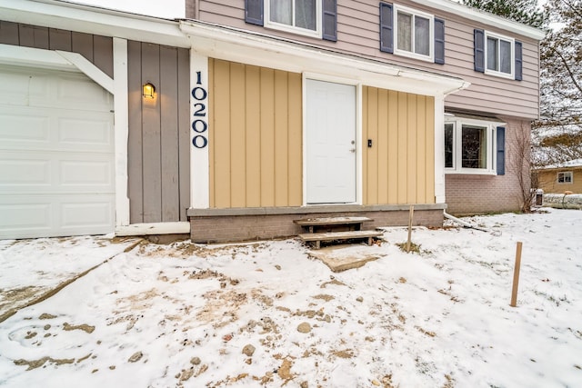 snow covered property entrance featuring a garage