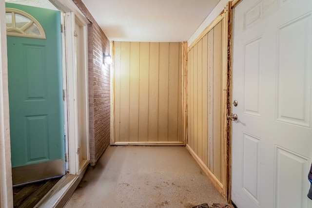 doorway featuring brick wall and wooden walls