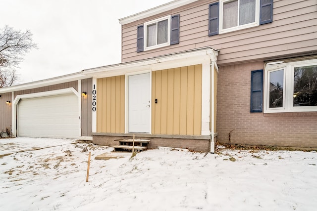 snow covered property entrance with a garage