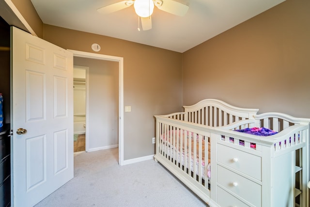 carpeted bedroom with ceiling fan and a nursery area