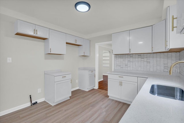 kitchen featuring backsplash, sink, white cabinets, and light hardwood / wood-style floors