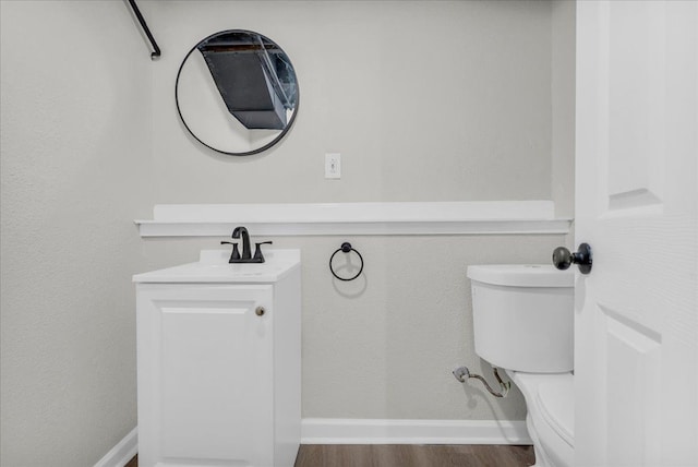 bathroom with wood-type flooring, vanity, and toilet