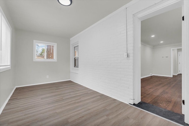 empty room featuring crown molding, brick wall, and dark hardwood / wood-style floors