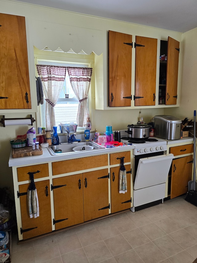 kitchen featuring white stove, light tile patterned floors, and sink