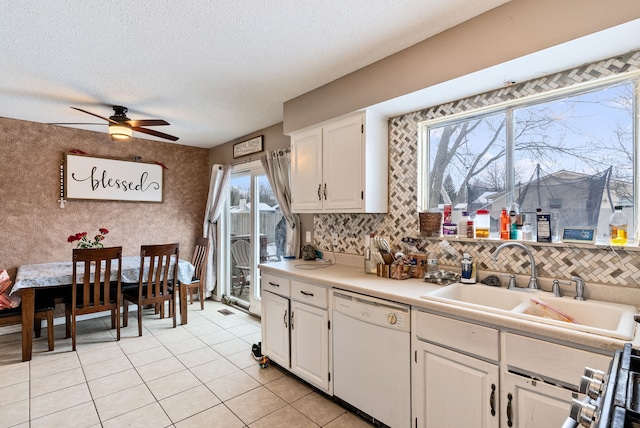 kitchen with white cabinets, white dishwasher, light tile patterned flooring, and sink