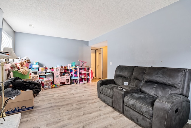 playroom featuring a textured ceiling and light hardwood / wood-style flooring