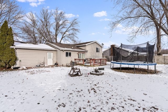 snow covered house featuring a trampoline and a deck