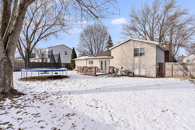 snow covered property featuring a trampoline and a wooden deck