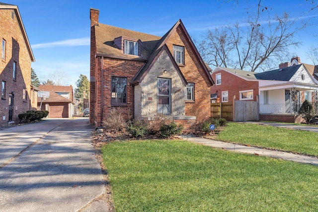 tudor house featuring a garage, an outbuilding, and a front lawn