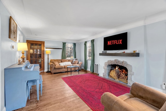 living room with hardwood / wood-style flooring, ornamental molding, and a fireplace