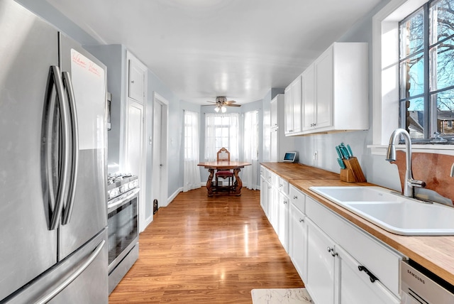 kitchen with sink, ceiling fan, appliances with stainless steel finishes, plenty of natural light, and white cabinetry