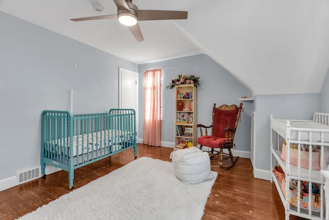 bedroom featuring lofted ceiling, ceiling fan, a crib, and hardwood / wood-style flooring