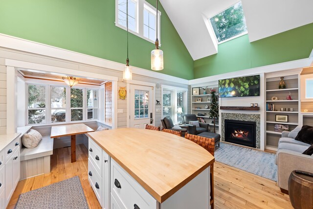 kitchen with a skylight, white cabinets, pendant lighting, and high vaulted ceiling