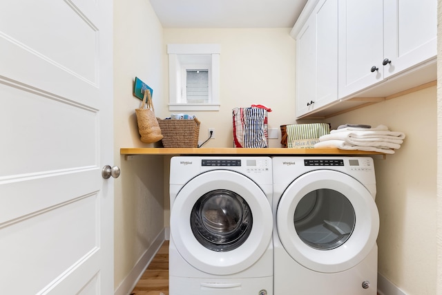 laundry area featuring hardwood / wood-style floors, washer and clothes dryer, and cabinets