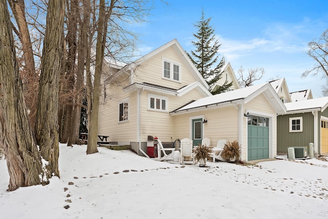 snow covered property with cooling unit and a garage