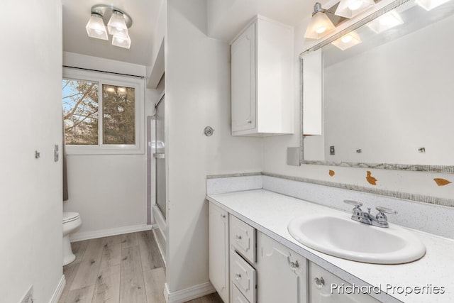 full bathroom with hardwood / wood-style floors, vanity, toilet, and shower / bath combination with glass door