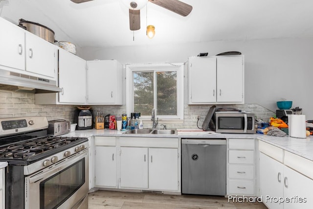 kitchen featuring appliances with stainless steel finishes, light wood-type flooring, tasteful backsplash, sink, and white cabinets