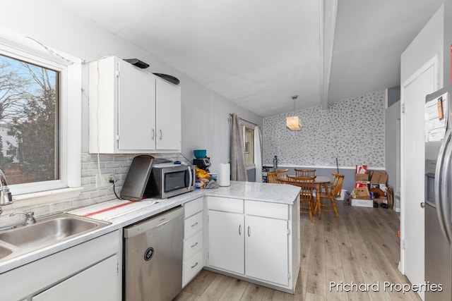 kitchen featuring stainless steel appliances, kitchen peninsula, decorative light fixtures, decorative backsplash, and white cabinets