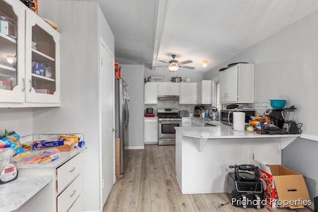 kitchen with backsplash, white cabinets, ceiling fan, kitchen peninsula, and stainless steel appliances