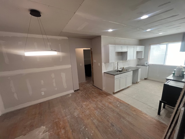 kitchen featuring backsplash, sink, light hardwood / wood-style floors, white cabinetry, and washer / clothes dryer