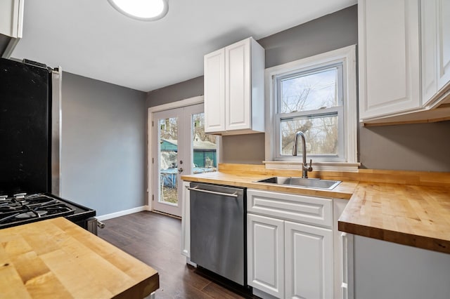 kitchen with stainless steel dishwasher, white cabinets, butcher block counters, and sink